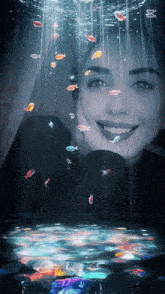 a woman is smiling underwater surrounded by fish and bubbles