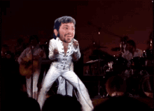 a man in a white suit is playing drums in a band