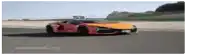 a red and orange car is driving down a road .