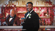 a man in a tuxedo is holding a drink in front of a bar that says monaco on it