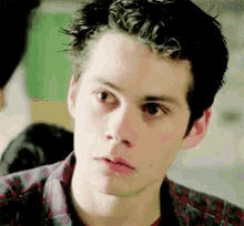 a close up of a young man 's face with a plaid shirt