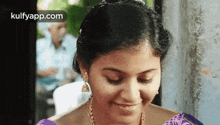 a woman is smiling with her eyes closed and wearing a purple top .