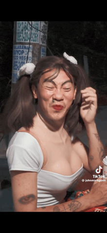 a man with pigtails and a tattoo on his arm is wearing a white shirt