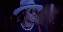 a man wearing a hat and sunglasses is making a funny face