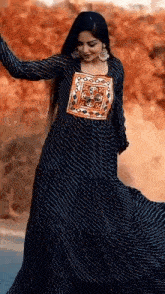 a woman in a long black dress is dancing on a street .