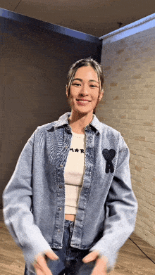 a woman wearing a blue denim jacket and a white shirt that says mar