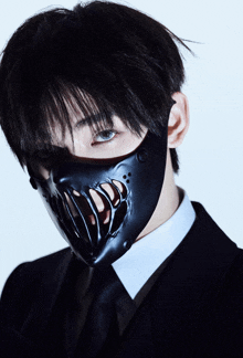 a man in a suit and tie wears a black mask on his face