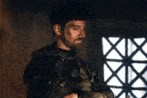 a man with a beard is standing in front of a window with a x on it