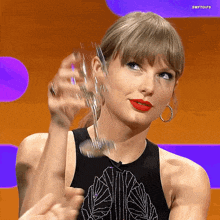 a woman in a black tank top holds a glass in her hand