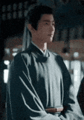a man in a kimono is standing with his arms crossed in front of a building .