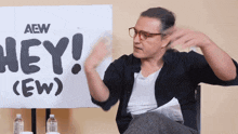 a man sitting in front of a sign that says " hey "