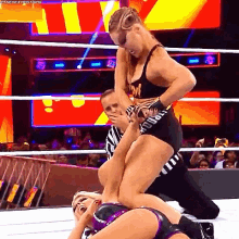 two female wrestlers are wrestling in a ring and one of them is wearing shorts with the letter w on them