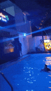 a person is swimming in a pool with a sign that says resort in the background