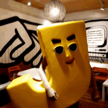 a person in a yellow letter j costume holds a disco ball above their head
