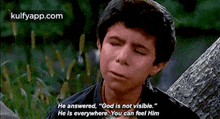 a young boy is sitting under a tree with his eyes closed .