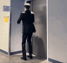 a man in a suit is standing in front of a door with a sign that says hyuwon