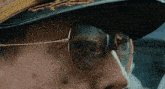 a close up of a person wearing sunglasses and a hat .