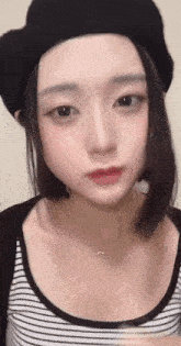 a close up of a woman wearing a hat and a striped shirt .