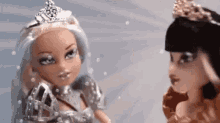 two dolls with tiaras on their heads standing next to each other