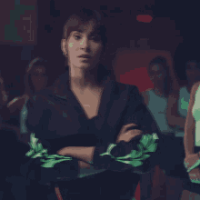 a woman in a black jacket with green sleeves is standing with her arms crossed