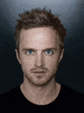 a close up of a man 's face with blue eyes and a beard