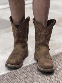 a pair of brown cowboy boots are on a person 's feet