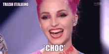 a woman with pink hair and red lips is laughing with the words choc on her face .