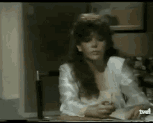 a woman is sitting at a desk holding a pen and a book .