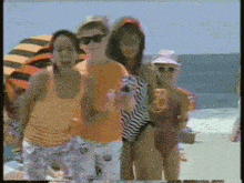 a group of people are standing on a beach holding drinks