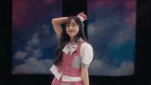 a girl in a pink and white dress is standing in front of a cloudy sky .