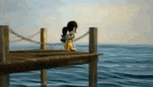 a person is sitting on a dock overlooking the ocean