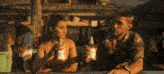 a man and a woman are sitting at a bar holding bottles of pabst beer