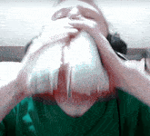 a man in a green shirt is drinking from a plastic container