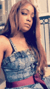 a woman wearing a denim dress with a red belt
