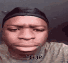 a man wearing a hat and a t-shirt is making a funny face and says `` your '' .