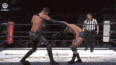 two wrestlers are fighting in a ring with a referee watching .