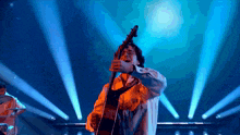 a man playing a guitar on a stage with blue lights