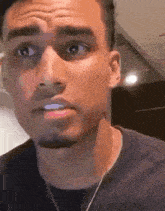a close up of a man 's face with a necklace around his neck making a funny face .
