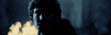 a man is standing in a dark room with a fire in the background .