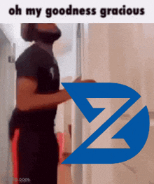 a man is standing in a hallway with a blue z on the wall