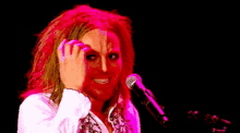 a woman with red hair is singing into a microphone and making a face