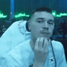 a man wearing headphones and a white shirt is sitting in a chair in a dark room .