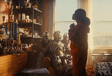 a woman standing next to a robot in a room with kepler written on the bottom right corner
