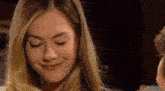 a close up of a woman 's face with her eyes closed and a smile on her face .
