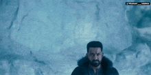 a man with a beard is standing in front of an ice wall with the words pranay and varma on the bottom