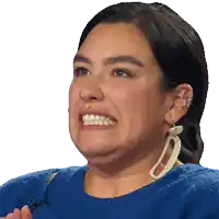a woman wearing a blue sweater and white earrings smiles for the camera