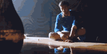 a man in a blue sweater sits on a wet floor