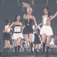 a group of women are standing on a stage holding hands and dancing .