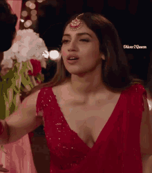 a woman in a red dress with a plunging neckline and a maang tikka on her forehead