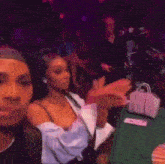 a woman is sitting at a table in a crowded room holding a cell phone in her hand .
